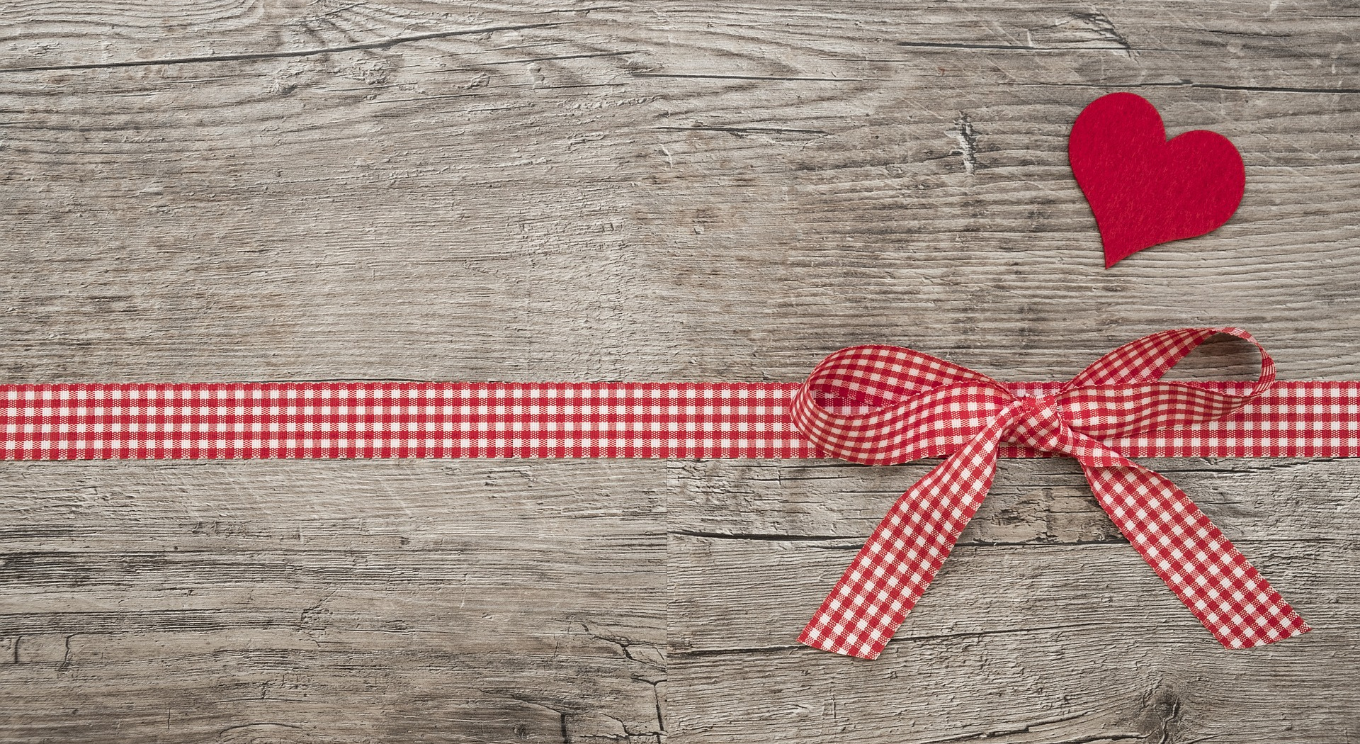 Place card with a red gingham bow and felt heart on gray barn wood