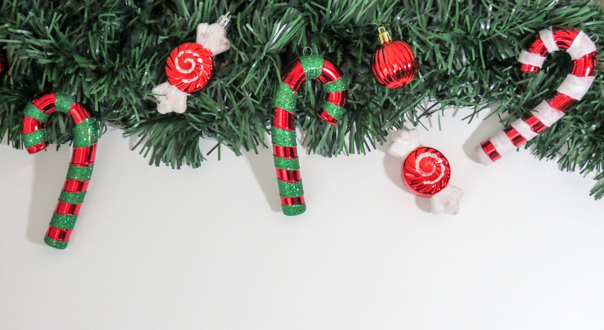 Place card with a pine garland, candy canes, and peppermints across the top