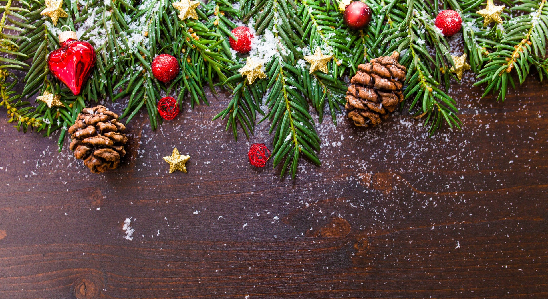 Place card photo of pine branches, pinecones and red ornaments on dark wood